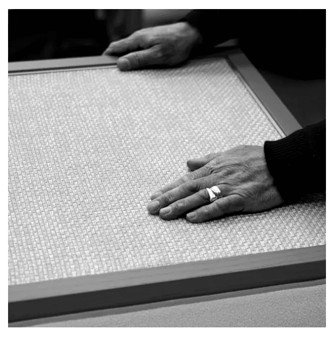 Hands on a framed woven craft panel